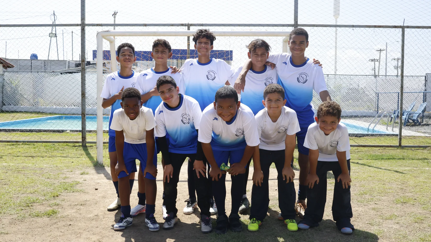 Grupo de estudiantes con uniforme deportivo frente a la portería de la cancha